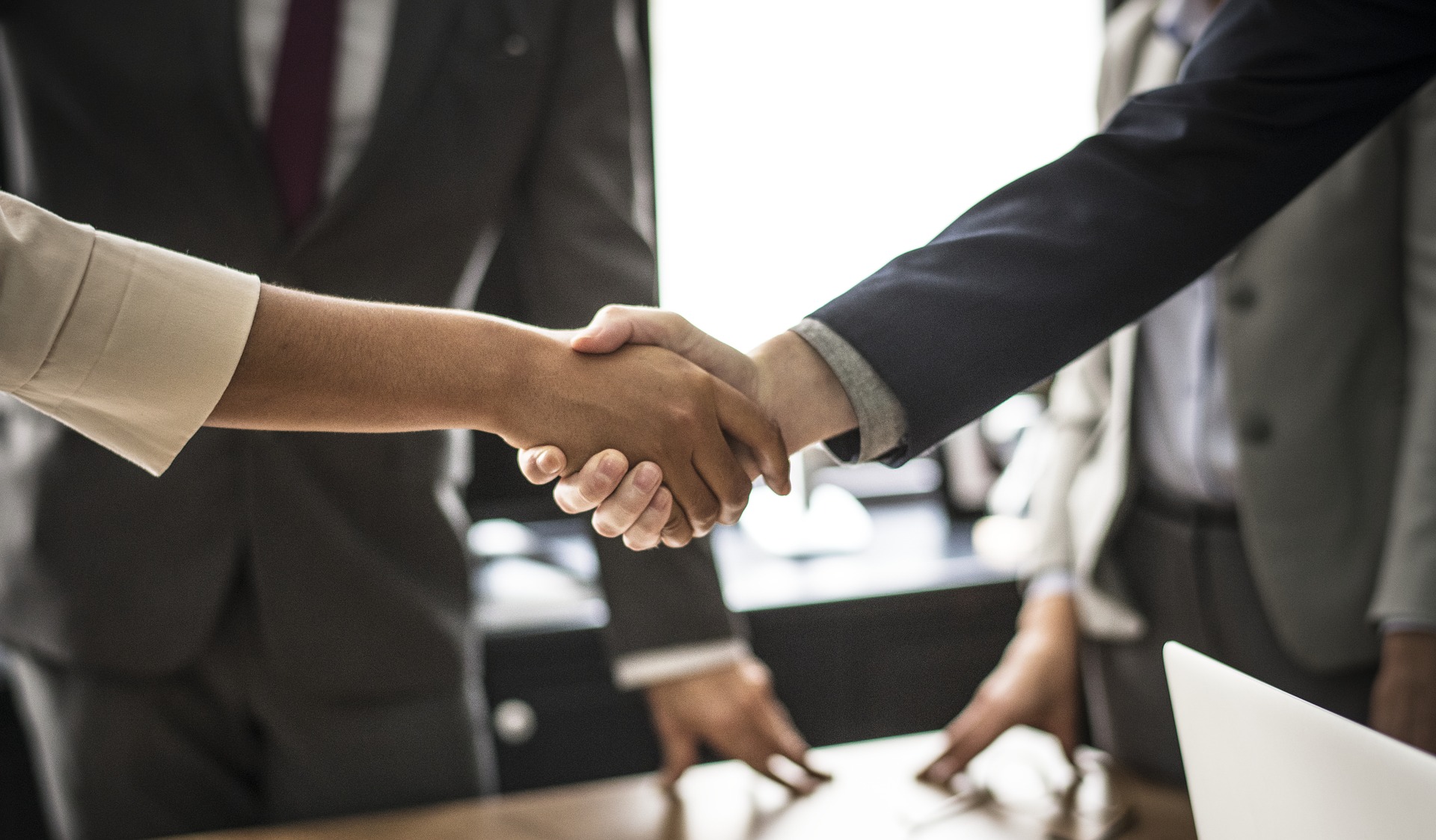 Two people shaking hands in an office setting.