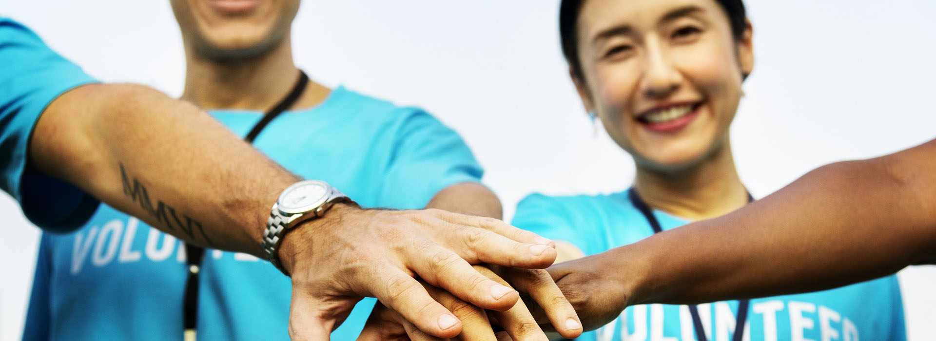People joining hands, wearing blue volunteer shirts.